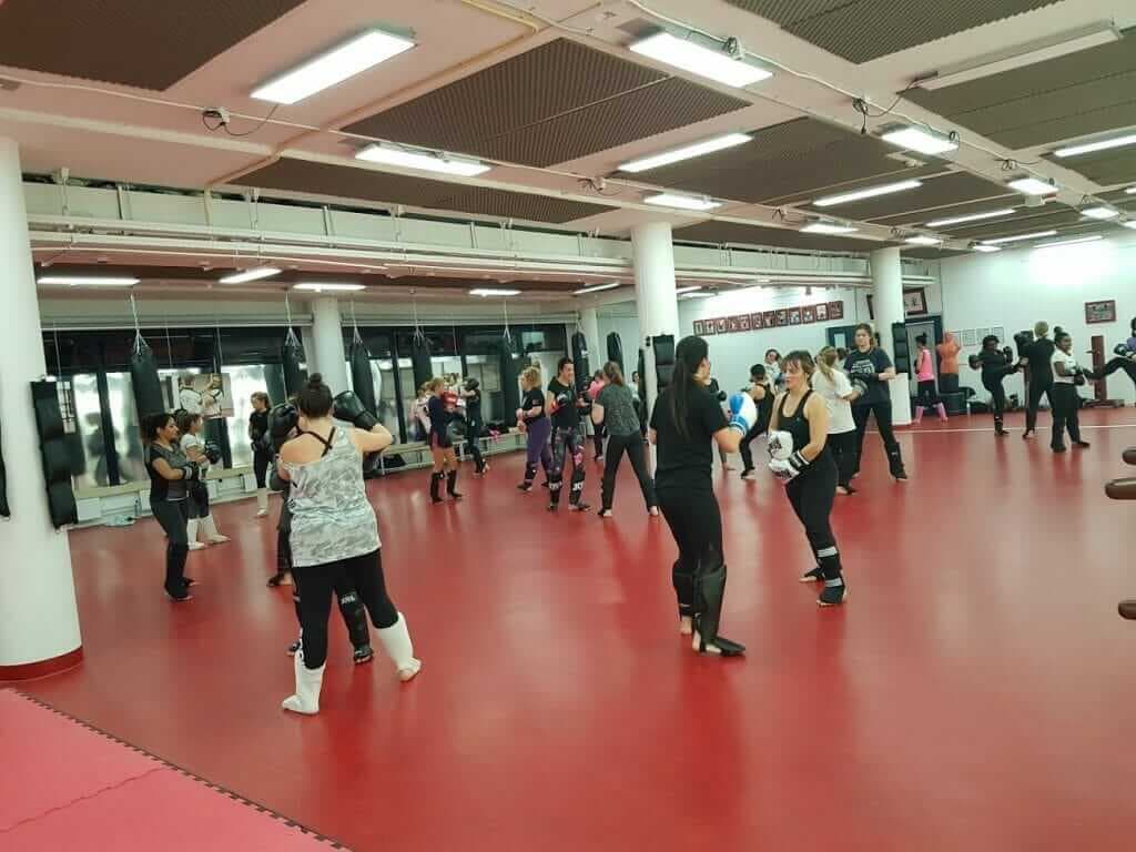 Een groepstraining in een grote sportzaal met een rode vloer
